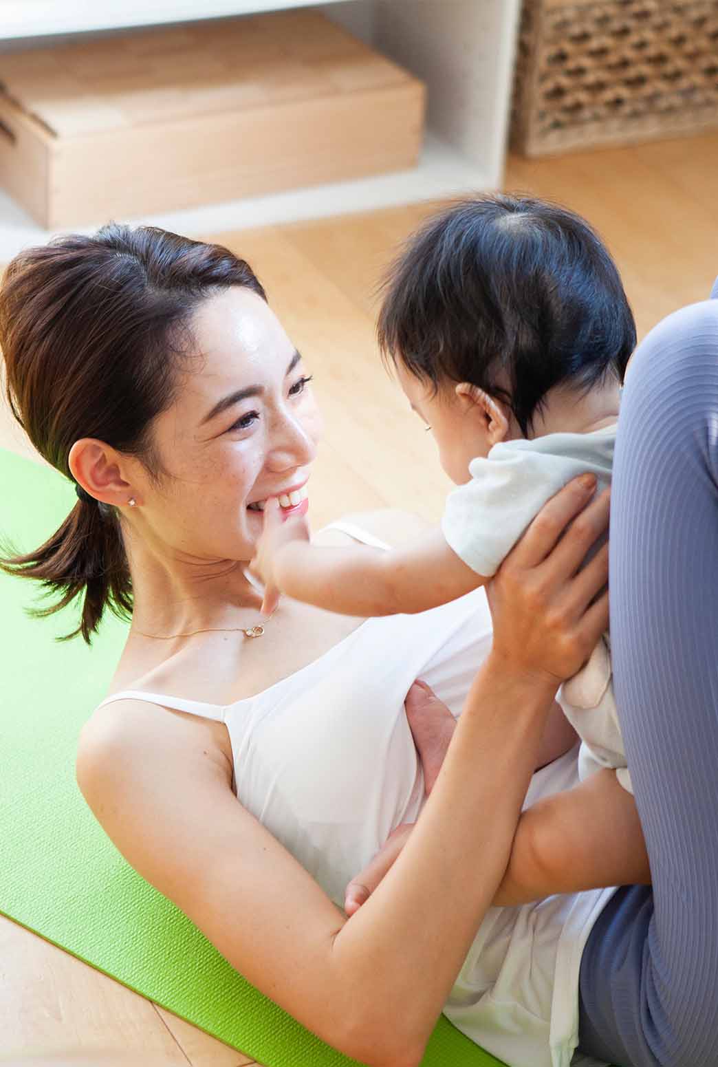 赤ちゃんと一緒に軽い運動（ヨガ）を楽しむママ